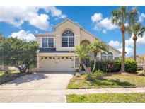 Charming two-story home featuring a two-car garage, arched windows, and lush landscaping with palm trees at 2806 Baywood Ln, Kissimmee, FL 34746