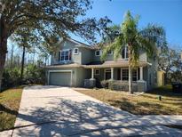 Two-story home with a well-manicured lawn and mature trees, offering curb appeal and shade at 602 Lochsmere Ln, Orlando, FL 32828