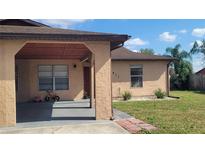 Beige single-story home featuring a covered carport and well-maintained landscaping on a sunny day at 7411 Golden Glenn Ct, Orlando, FL 32807