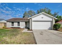 Charming single-story home features an attached two-car garage and a well-maintained front yard at 9913 Peddlers Way, Orlando, FL 32817