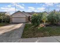 Charming single-story home featuring a two-car garage and mature palm trees in the front yard at 12972 Broakfield Cir, Orlando, FL 32837