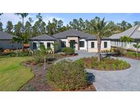 Beautiful single story home boasts a circular driveway, lush landscaping and mature palm trees at 17102 Medici Way, Bella Collina, FL 34756