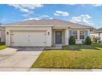 Charming single-story home featuring a two-car garage, gray door, manicured lawn, and beautiful blue shutters at 1751 Sereno Dr, Davenport, FL 33896