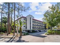 Exterior shot of a multi-story condo with a red roof and ample parking at 200 El Camino Dr # 402, Winter Haven, FL 33884