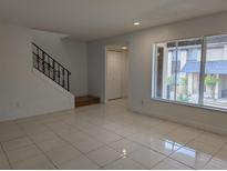 Bright living room with tile flooring, staircase, and natural light from a window at 5415 Fairwood Way # 303, Orlando, FL 32808