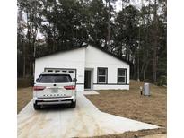 Charming single-story home featuring a white exterior, black trim, and a concrete driveway at 6937 Se 23 Ave, Ocala, FL 34480