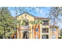 Colorful condominium exterior showing balconies and stairs surrounded by lush Florida landscaping and palm trees at 713 Crest Pines Dr # 227, Orlando, FL 32828