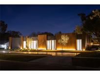 Stunning modern home with a unique wood and steel exterior, illuminated landscaping, and a sleek driveway at 8966 Easterling Dr, Orlando, FL 32819