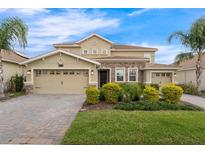 Charming two-story home with a two-car garage, brick driveway, stone accents, and well-manicured landscaping at 8995 Croquet Ct, Champions Gate, FL 33896