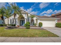 Charming home featuring a lush lawn, palm trees, and an attached two-car garage at 13537 Ivy Brooke Ln, Orlando, FL 32828
