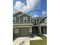 Two-story townhome featuring a two-car garage and neutral-tone horizontal siding at 9436 Westside Hills Dr, Davenport, FL 33896
