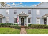 Charming two-story townhouse featuring a brick walkway, manicured landscaping, and an inviting covered entryway at 14216 Mailer Blvd, Orlando, FL 32828