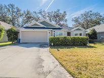 Charming single-story home features a well-manicured lawn, mature trees, and an attached two-car garage at 2936 Suber St, The Villages, FL 32163