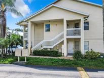 Exterior of two story condo building featuring white stairs and tropical landscaping at 3208 Sabal Palms Ct # A, Kissimmee, FL 34747