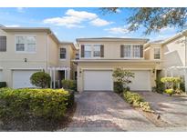 Charming townhome featuring a one-car garage and a beautifully landscaped front yard with a brick paved driveway at 3257 Villa Strada Way, Orlando, FL 32835