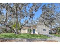 Charming home featuring a well-manicured lawn, mature trees, and welcoming blue front door at 388 Winnway St, Apopka, FL 32712