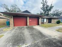 Home's brick facade and two-car garage with red doors offer curb appeal at 3913 Rose Of Sharon Dr, Orlando, FL 32808