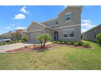 Charming two-story home featuring a two-car garage, manicured lawn, and decorative landscaping at 9180 Carmela Ave, Davenport, FL 33897