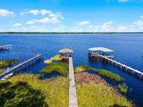 Beautiful aerial view of the lake house with private dock and boat house under blue skies at 13344 S Lake Mary Jane Rd, Orlando, FL 32832