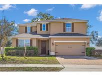 Charming two-story home showcasing a well-manicured lawn, a brick paver driveway, and a welcoming two-car garage at 1465 Osprey Ridge Dr, Eustis, FL 32736