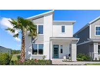 Modern two-story home with a blue door, complemented by a palm tree and manicured landscaping at 2026 Education St, St Cloud, FL 34771