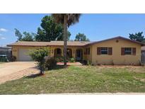 Charming single-story home with a well-maintained lawn and mature landscaping, complemented by a beautiful palm tree at 210 Dartmouth St, Deltona, FL 32725