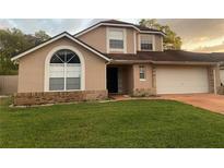 Charming two-story home features a manicured lawn, attached garage, and a welcoming facade with large windows at 7138 Hiawassee Bent Cir, Orlando, FL 32818