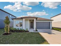 Charming one-story home with a well-manicured lawn, blue paint, and a gray two-car garage at 1453 Arbor Hill Dr, Deltona, FL 32725