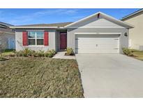 Charming one-story home featuring a two car garage, red shutters, and a red front door at 1925 Arbor Mill Ln, Kissimmee, FL 34744