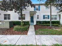 Charming two-story townhouse featuring a well-maintained front yard and a welcoming blue front door at 2840 Grasmere View Pkwy, Kissimmee, FL 34746