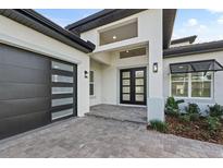 Elegant front entrance with double doors, modern garage door, and sleek architectural details at 336 Caladium Ave, Lake Alfred, FL 33850
