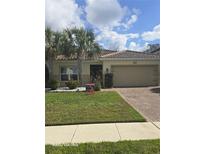 Charming single-story home featuring a tile roof, lush lawn, and mature palm trees at 3869 Carrick Bend, Kissimmee, FL 34746