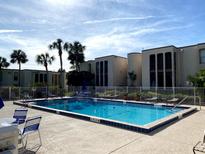 Community pool with ample seating surrounded by lush, tropical landscaping on a sunny day at 516 Orange Dr # 17, Altamonte Springs, FL 32701