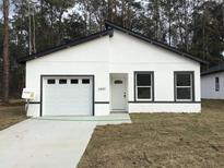 Modern home showcasing a well-manicured lawn, a white facade with dark trim and an attached one car garage at 6889 Se 23 Ave, Ocala, FL 34480