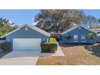 Charming blue home featuring an attached two-car garage, manicured bushes, and a lovely front entrance at 1320 Corte Nueva, Winter Springs, FL 32708
