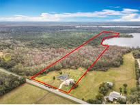 Expansive aerial view of a large lot home with a backdrop of lush trees and a lake at 1680 Blackwelder Rd, De Leon Springs, FL 32130