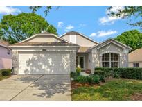 Charming single-Gathering home featuring a two-car garage, well-manicured lawn, and inviting front entrance at 2308 Edmonton Ct, Clermont, FL 34711