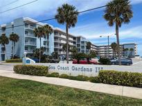 Sea Coast Gardens III complex showcases a blue exterior, tropical landscaping, and ample parking under a sunny sky at 4153 S Atlantic Ave # 1070, New Smyrna Beach, FL 32169