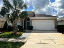 Charming one-story home with a well-manicured lawn, palm tree, and a two-car garage at 8157 Fan Palm Way, Kissimmee, FL 34747