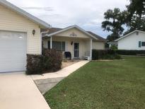 Charming single-story home with a well-manicured lawn, covered porch, and attached garage at 10839 Sw 78Th Ct, Ocala, FL 34476