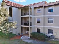 Three-story condo building featuring a spanish tile roof, beige exterior, and private balconies at 3016 Parkway Blvd # 110, Kissimmee, FL 34747