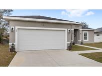 Exterior view of a one-story home showcasing a two-car garage and well-maintained front lawn at 42 Willow Ln, Poinciana, FL 34759