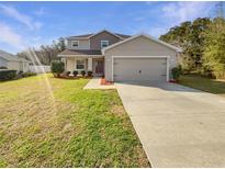 Charming two-story home with neutral paint, large garage, well-maintained lawn and mature trees at 11392 Sw 58Th Cir, Ocala, FL 34476