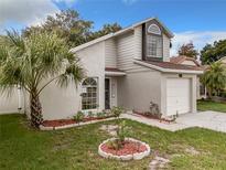 Charming two-story home featuring a well manicured lawn, tropical landscaping, and an attached one car garage at 1970 Larkwood Dr, Apopka, FL 32703