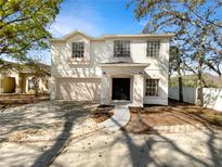 Charming two-story home features a two-car garage, light pink accents and a well maintained front yard at 3230 Buck Hill Pl, Orlando, FL 32817