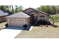 Charming single Gathering home featuring a two-car garage and lush landscaping at 680 Caribou Ct, Apopka, FL 32703