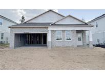 Unfinished block home featuring a two-car garage and covered front porch, offering a blank canvas for customization at 768 Pointe Emerson Blvd, Apopka, FL 32703