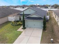 Charming home featuring a two-car garage, well-maintained lawn, and mature landscaping at 1230 Woodlark Dr, Haines City, FL 33844