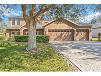 Well-maintained two-story home with a three-car garage and a lush green lawn at 1037 Truffles Ct, Apopka, FL 32712