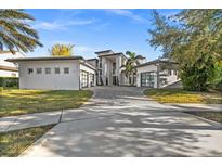 Stunning contemporary home showcasing a grand entrance, lush landscaping, and dual garages, all under a vibrant blue sky at 12264 Montalcino Cir, Windermere, FL 34786